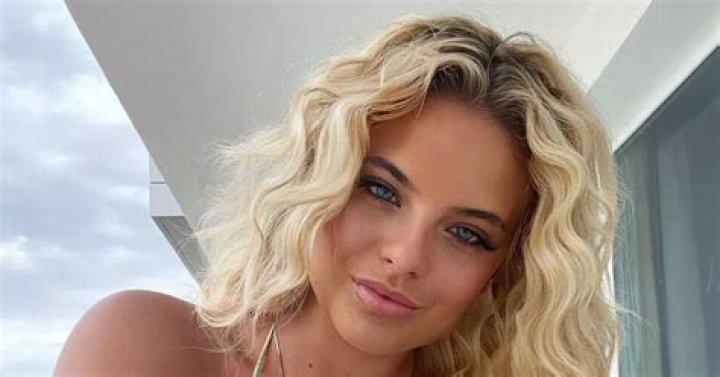 Busty boxing ring girl Apollonia Llewellyn shows off her tan lines as she nearly spills out of skimpy gold bikini