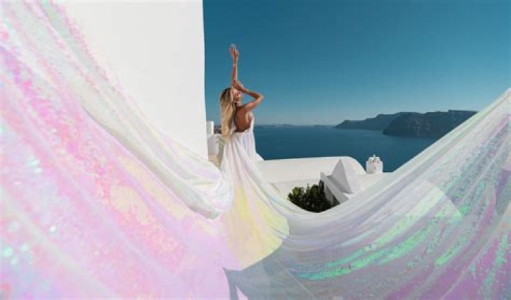 World's sexiest volleyball player Kayla Simmons sips from wine glass in low-cut summer dress on Santorini vacation